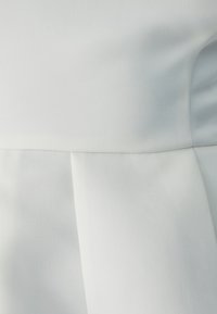 White dress with a smooth texture, featuring subtle pleats and a structured design. The fabric has a slight sheen and a tailored silhouette.