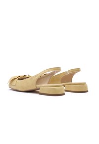 Žute antilop sandale s remenčićem na petu, ukrašene mašnom, s niskom blok petom i otvorenim stražnjim dijelom. Glatka tekstura s laganim, mat završetkom.