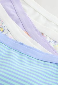 Pile de sous-vêtements en coton aux couleurs pastel avec des bords festonnés et des motifs doux, comprenant des rayures, des fleurs et des unis.