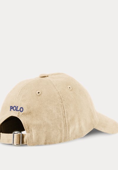 Casquette de baseball beige avec sangle réglable et boucle métallique, brodée du mot "POLO" en bleu sur le côté arrière gauche.