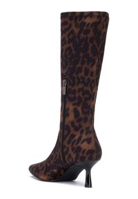 Bota de caña alta con estampado de leopardo en tela marrón y negra, con cremallera lateral y un tacón delgado y afilado. Textura suave y puntera en punta.