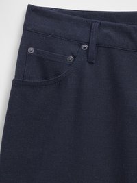 Tmavomodré denimmové nohavice s prednou kapsou, dvoma kovovými gombíkmi a kontrastným prešívaním pozdĺž pásu a vreciek.