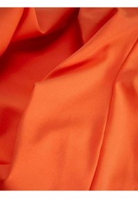 Jasně oranžová tkanina s hladkým povrchem, splývající v jemných faldcích. Materiál vypadá lehký a má mírný lesk.