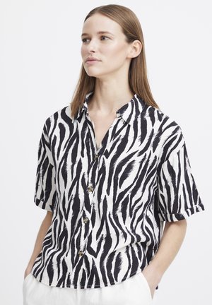 Chemise à manches courtes avec un motif rayé zèbre noir et blanc. Elle possède un devant boutonné et une coupe décontractée avec un col.