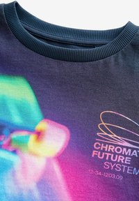 Langärmliger Sweatshirt mit einer strukturierten marineblauen Kragen, versehen mit einem Farbverlauf in Farben wie Blaugrün, Pink und Gelb sowie einem weißen Logo.