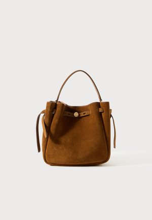 Sac à main en cuir suédé marron avec une forme structurée, doté d'une anse supérieure, de sangles latérales ajustables et d'un petit accent en bouton à l'avant.