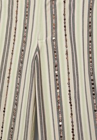 Tissu à rayures verticales avec des lignes vert clair, grises et blanches décoré de rangées verticales de petits sequins brillants.
