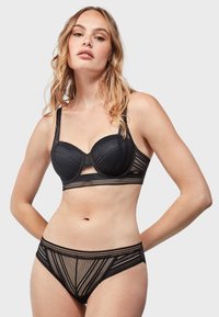 Conjunto de lencería negra que presenta un sujetador estructurado con detalles de encaje y acentos de malla, combinado con bragas estilo bikini de malla.