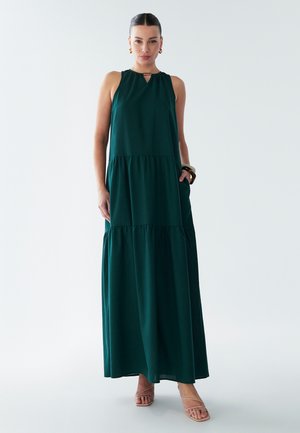 Grøn maxi kjole med ærmeløs design, nøglehulshalsudskæring, lagdelt nederdel og lommer. Lavet af et blødt, flydende stof.