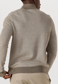 Beige gestrickter Pullover mit einem strukturierten Fischgrätenmuster, gerippten Bündchen und Saum. Der Stehkragen ergänzt den Gesamtlook.