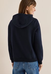 Felpa blu navy con un design testurizzato "MOMENT" sul cappuccio, caratterizzata da un tessuto morbido, polsini a coste e una vestibilità rilassata.