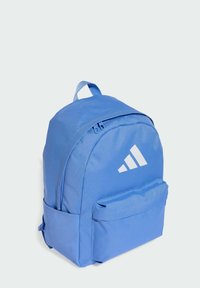Mochila de poliéster azul con forma redondeada, que cuenta con un compartimento principal con cremallera, un bolsillo frontal y el logo blanco de adidas.