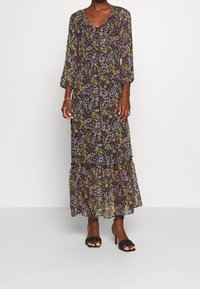 Robe longue à imprimé floral avec un col en V, des manches longues et un ourlet à volants multiples. Fabriquée en tissu léger et transparent aux couleurs sombres avec des accents colorés.