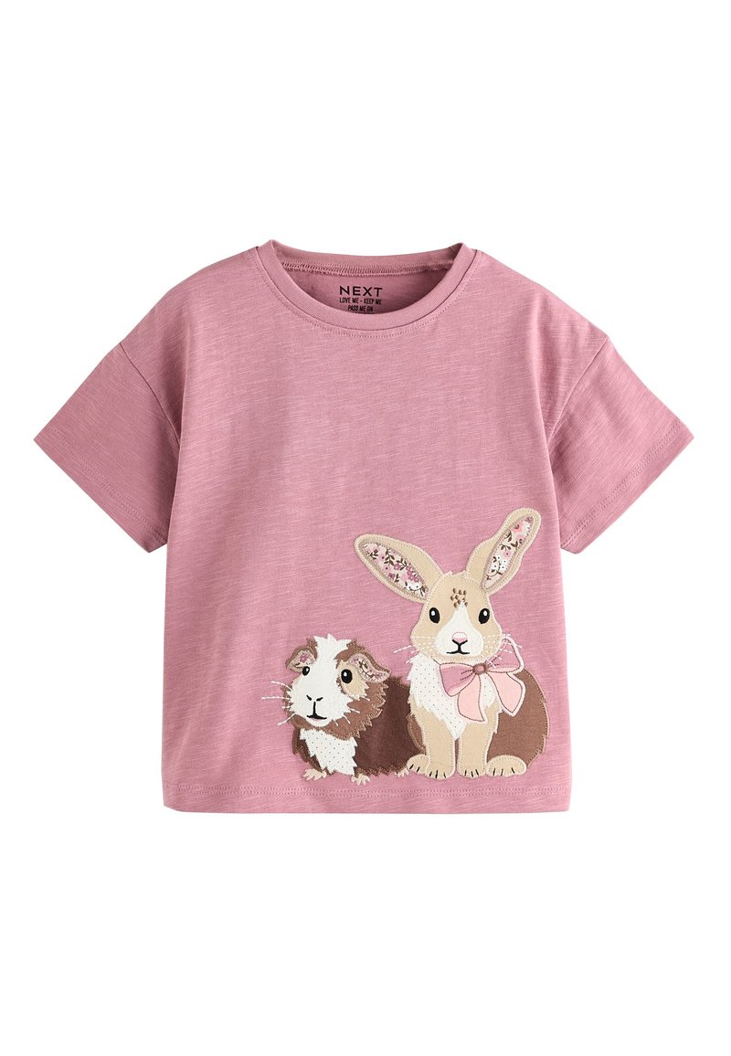 T-shirt rose à manches courtes en tissu doux, ornée de motifs brodés de cobayes et de lapins avec un nœud rose. Encolure ronde, coupe décontractée.