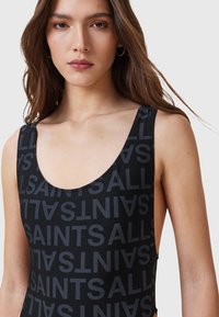 Costume da bagno nero con scollatura a barca e un audace motivo testuale "SAINTS" in finitura opaca, realizzato in tessuto liscio ed elastico.