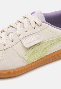 Puma Palermo sportcipők, bézs velúr felsőrésszel, zöld texturált oldaldetállal és világoslila kiegészítőkkel. Gumi talp logós márkajelzéssel.
