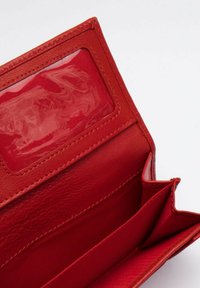 Interno di un portafoglio in pelle rossa con uno slot per ID trasparente, texture liscia, due scomparti e un elegante bordo cucito.