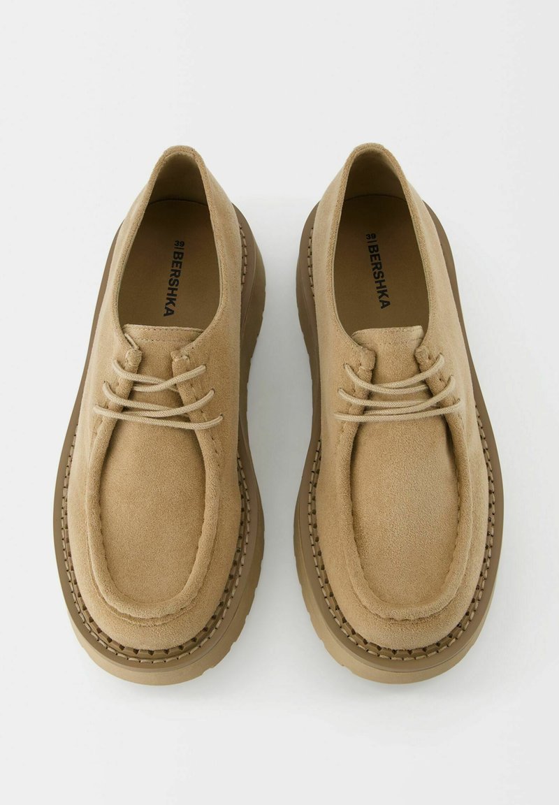 Zapatos de ante beige con cordones, suelas de goma gruesas y detalles cosidos sobre un fondo blanco, talla 39 de Bershka.