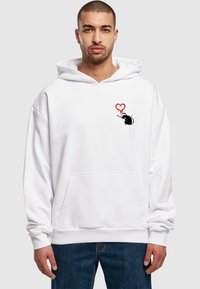 Felpa bianca con cappuccio e tasca anteriore, decorata con una grafica di un topo nero e un cuore rosso, realizzata in tessuto morbido e con una vestibilità ampia.