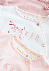 Tre body neonato in cotone rosa e bianco. Le caratteristiche includono il testo in rilievo "BAKER", un nastro decorativo e chiusure a pressione. Etichette visibili all'interno.
