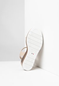 Beige sandal with white rubber sole. Features a smooth upper and a contoured, textured outsole. Logo and country of manufacture visible.