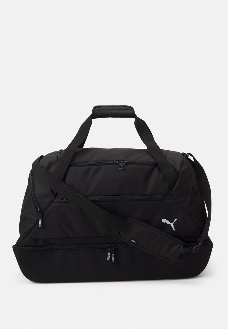 Mustapukuinen duffel-laukku, jossa on kaksinkertaiset yläkahvat, säädettävä olkahihna, kaksi vetoketjullista osastoa ja valkoinen Puma-logo sivussa.