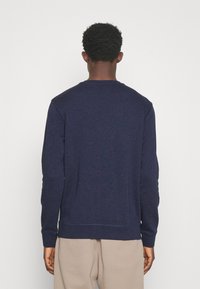 Sweatshirt azul-marinho com decote redondo, mangas longas e punhos em ribana. Textura suave e detalhe de costura subtil na bainha e nas mangas.