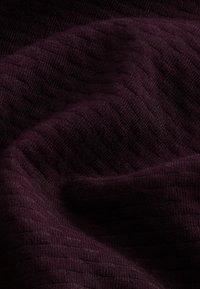 Tissu en tricot texturé de couleur bordeaux profond, avec des rayures verticales subtiles, une texture douce et un léger éclat. Idéal pour les vêtements ou le rembourrage.