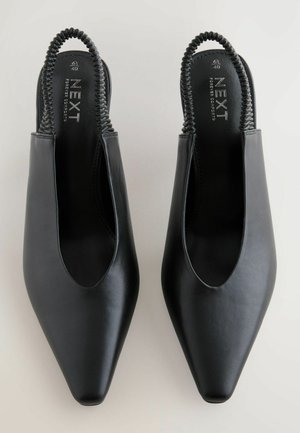 Zwarte leren slingback schoenen met een spitse neus, voorzien van een uitgesneden ontwerp en een textuur van zwart elastiek bij de hiel.