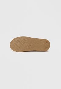 Semelle de chaussure en caoutchouc brun avec un texte en relief et une surface texturée. Forme arrondie avec un léger rétrécissement au niveau de la pointe.