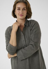 Heather színű gombos ing, állógallérral, felhurkoltujjakkal és laza fitfokkal. Az anyag puhanak tűnik, finom textúrával.