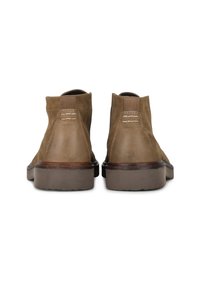 Botas de tobillo de cuero marrón con una textura suave, detalles de costura, paneles laterales elásticos y una suela de goma resistente.