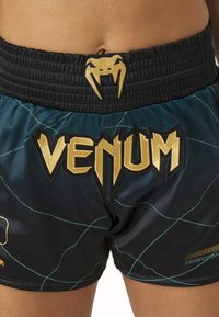 Μαύρες και τουρκουάζ σορτς με χρυσό ραμμένο λογότυπο "Venum", σχέδιο φιδιού στην ελαστική ζώνη και κομψή, λεία υφή.