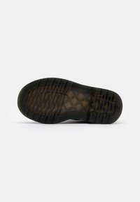 Suola di scarpa in gomma nera con superficie texture e motivo a battistrada rettangolare. La sezione trasparente rivela il materiale di ammortizzazione interno.