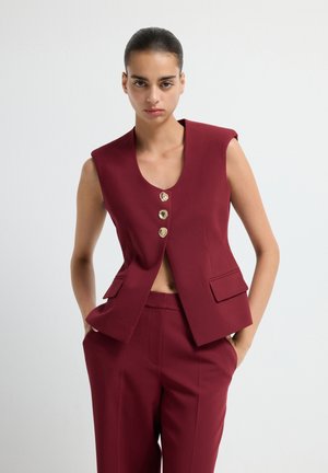 Burgundy sleeveless blazer with three gold buttons, V-neckline, and two front pockets, paired with matching tailored trousers.