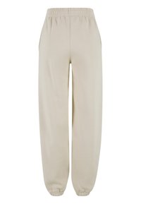 Pantalon décontracté beige avec taille et poignets élastiques, doté de poches latérales et d'une coupe ample et confortable.