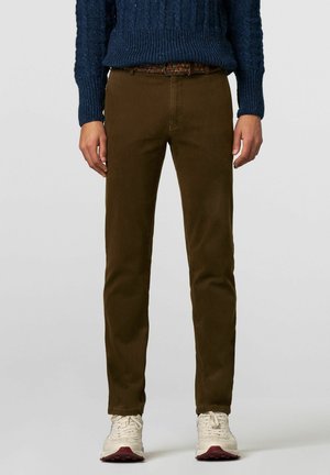 Pantalon en velours côtelé vert olive avec une coupe slim, taille moyenne et design à cinq poches, associé à une ceinture tissée colorée et des baskets blanches.