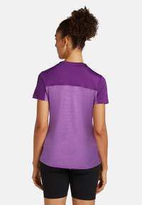 T-shirt de sport violet avec un design dégradé, à manches courtes et un col rond simple. Porté avec un short noir. Texture douce.