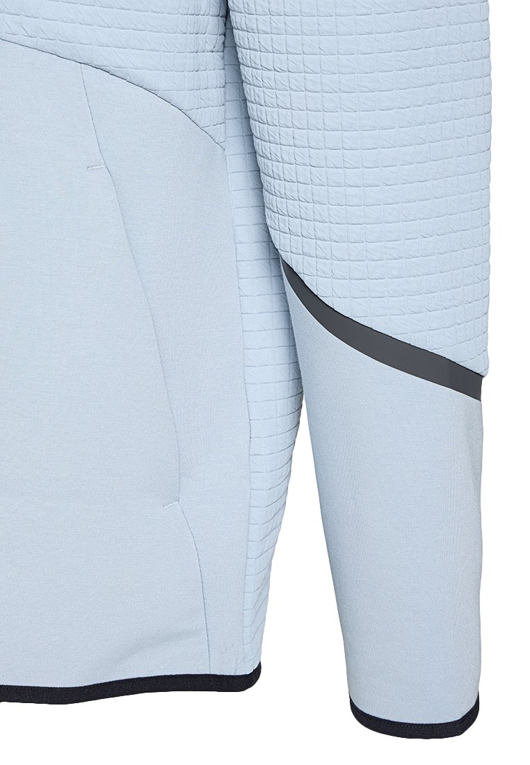Manche de veste matelassée bleu clair avec des panneaux en tissu lisse et une bande d'accent gris foncé en biais près du coude.