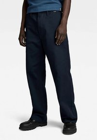 Tumši zili brīvā stila bikses no izturīga auduma ar sānu kabatām, gludu virsmu un taisna piegriezuma kājām.