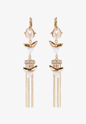 Boucles d'oreilles en ton or combinant coquillage et accents blancs, avec des chaînes et des détails en cristal pour une texture et un intérêt visuel supplémentaires.