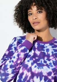 Felpa a maniche lunghe con motivo tie-dye viola. Presenta vivaci pattern nelle tonalità di blu e rosa, colletto e polsini a coste. Tessuto morbido.