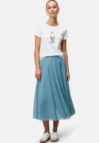 T-shirt blanc avec un graphisme coloré de crème glacée, associé à une jupe fluide de couleur bleu clair. Des baskets blanches complètent la tenue.