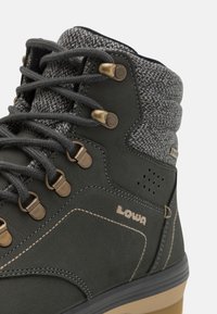 Donkergroene leren wandelschoen met een gestructureerde grijze stoffen kraag, bronzen hardware, versterkte veterogen en een lichtbruine zool.