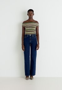 Off-the-shoulder striped top in green and brown hues paired with high-waisted blue denim jeans, featuring a relaxed fit and smooth texture.