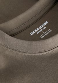 Brun bomulds t-shirt med rund halsudskæring og blød tekstur. Label angiver størrelse L, med mærkenavn og fremstillingsland.