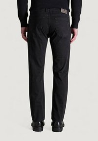 Pantalones de mezclilla negra con corte recto, que cuentan con dos bolsillos traseros y una etiqueta de la marca en la cinturilla. Textura suave y diseño minimalista.