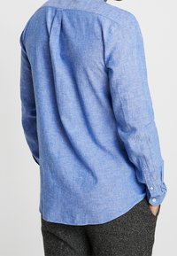 Lichtblauw overhemd met lange mouwen van gestructureerde stof, voorzien van een rugplooi, knoopmanchetten en een ontspannen pasvorm.