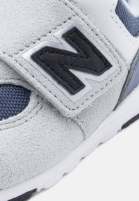 Γκρι σουέντ αθλητικό παπούτσι με navy δίχτυ, μαύρο δερμάτινο λογότυπο και λευκή λαστιχένια σόλα με λεπτομερή ραφή.