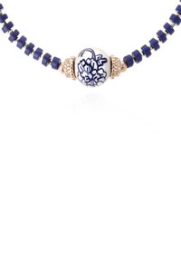 Collier en perles comprenant des perles en céramique bleu marine avec des accents dorés. La perle centrale ronde arbore une base blanche avec un motif floral bleu.